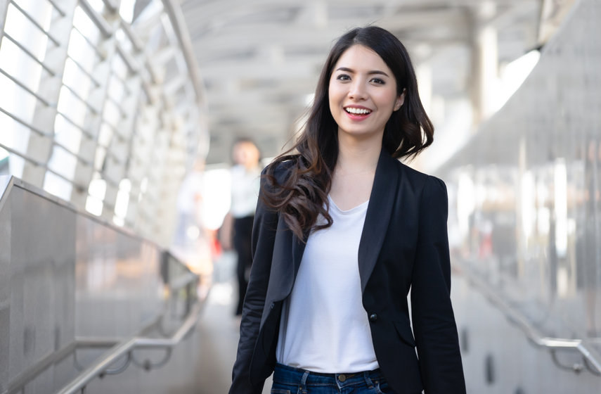 Young elegant business woman looking at camera and walking along